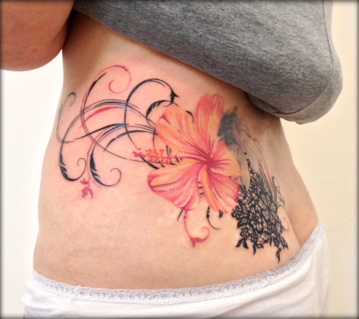 Female tattoo of pink flower and black lace